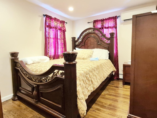 bedroom featuring recessed lighting, an AC wall unit, baseboards, and wood finished floors