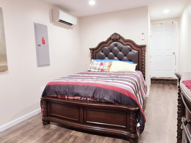 bedroom with electric panel, baseboards, wood finished floors, a wall mounted AC, and recessed lighting