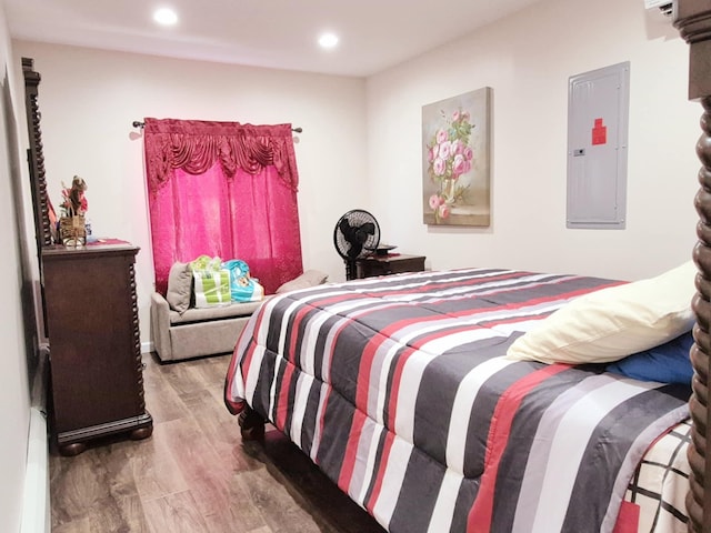 bedroom with electric panel, wood finished floors, and recessed lighting