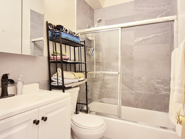 full bathroom featuring combined bath / shower with glass door, vanity, and toilet