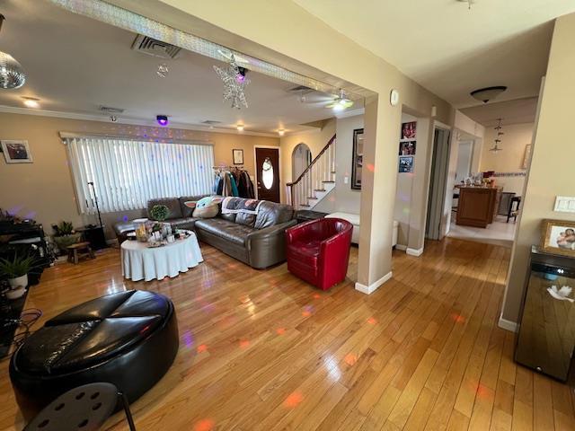 living area featuring hardwood / wood-style flooring, visible vents, baseboards, and stairs