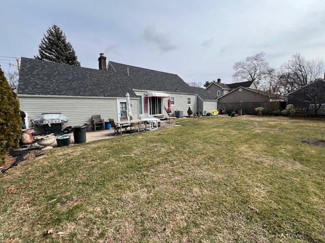 rear view of house featuring a patio area, a yard, and a chimney