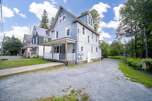 view of front of home featuring driveway, covered porch, and metal roof