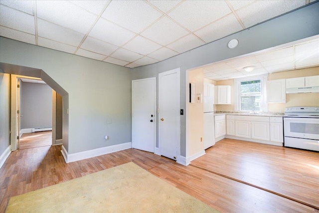 kitchen featuring arched walkways, white appliances, a drop ceiling, and white cabinetry