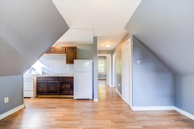 kitchen with light wood finished floors, gas range oven, freestanding refrigerator, and baseboards