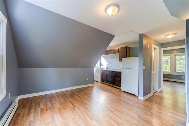 additional living space with light wood-type flooring, baseboards, a baseboard heating unit, and lofted ceiling