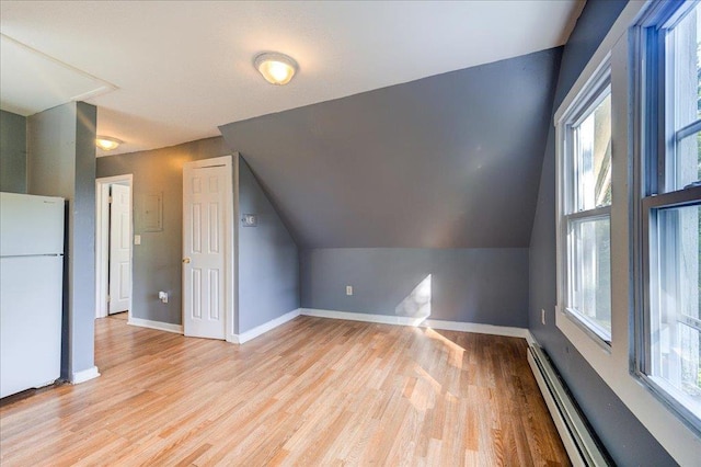 bonus room featuring a baseboard heating unit, vaulted ceiling, light wood-style flooring, and baseboards