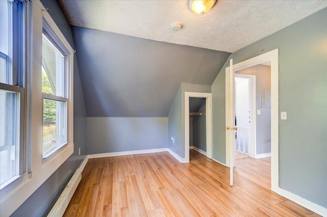 additional living space with vaulted ceiling, baseboards, and wood finished floors