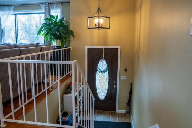 foyer featuring baseboards, wood finished floors, and an inviting chandelier