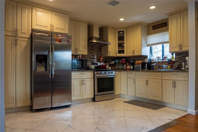 kitchen featuring visible vents, marble finish floor, cream cabinetry, appliances with stainless steel finishes, and wall chimney range hood