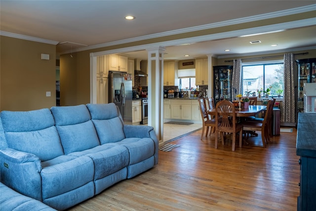 living room with plenty of natural light, attic access, light wood-style flooring, and ornamental molding