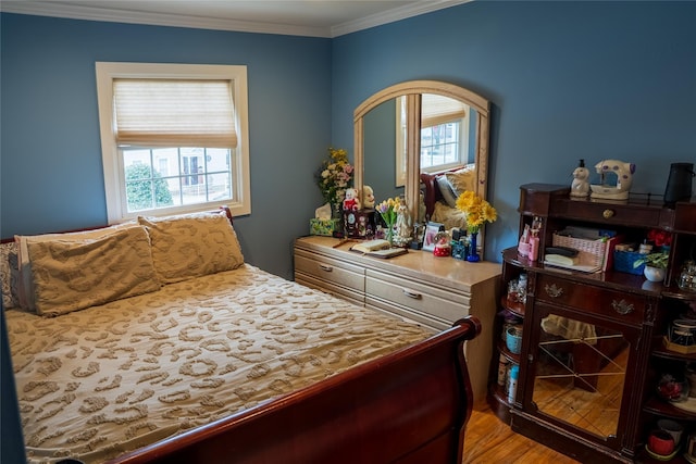 bedroom featuring ornamental molding, multiple windows, and light wood-type flooring