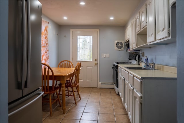 kitchen featuring range with gas cooktop, freestanding refrigerator, light countertops, a sink, and light tile patterned flooring