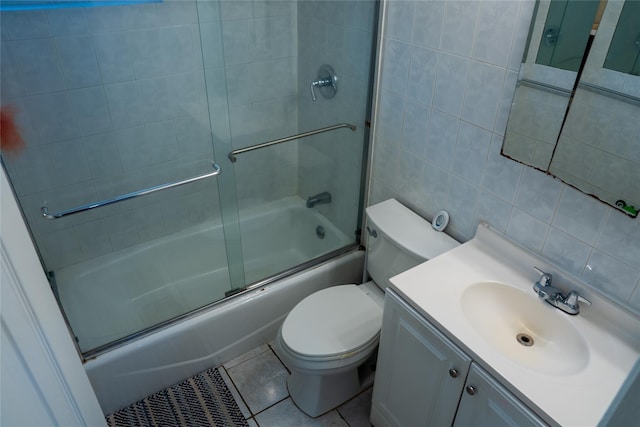 full bath featuring tile walls, toilet, combined bath / shower with glass door, vanity, and tile patterned flooring