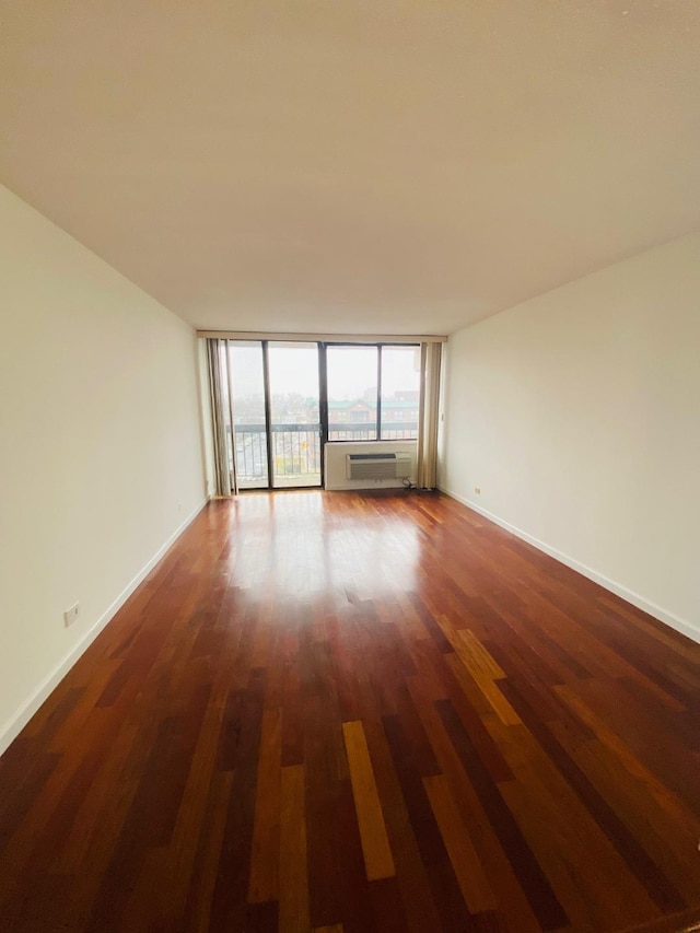 empty room featuring dark wood-style floors, expansive windows, and baseboards