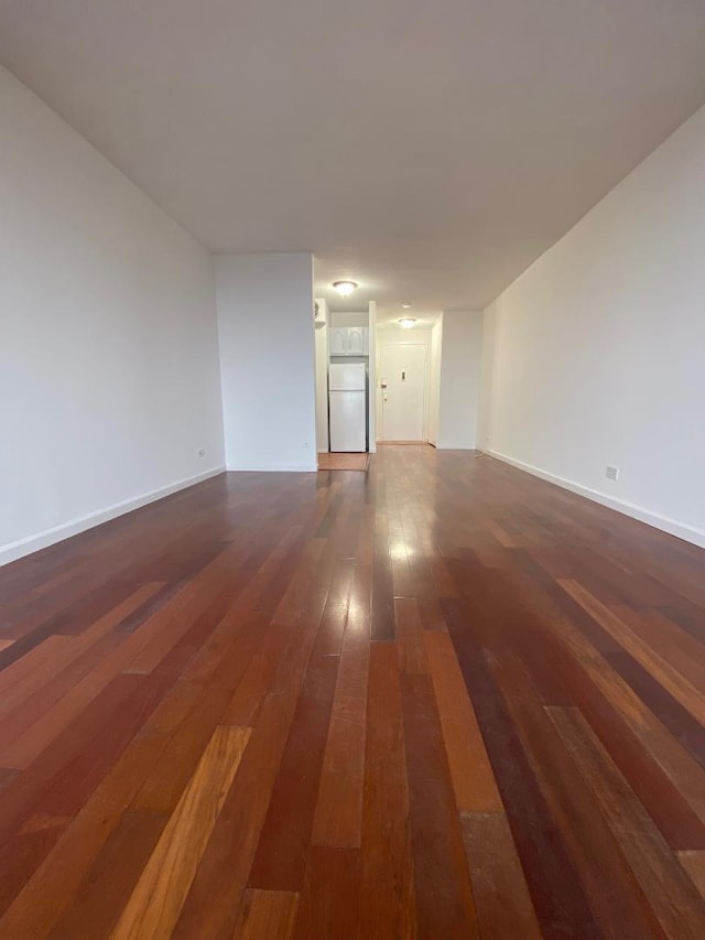 spare room featuring baseboards and dark wood finished floors