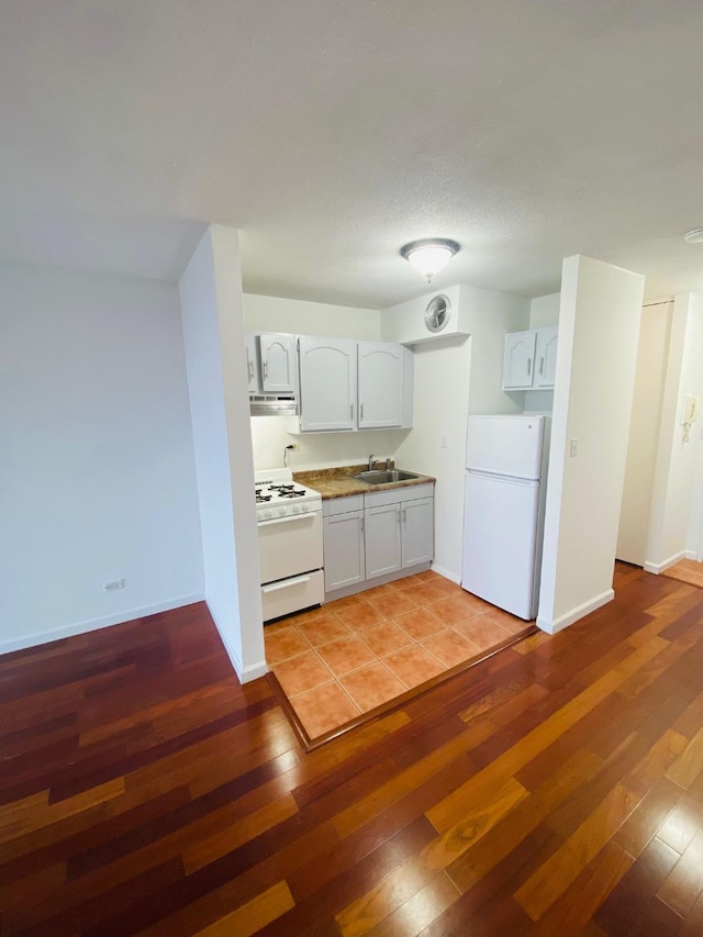 kitchen featuring light wood-style floors, a sink, white appliances, under cabinet range hood, and baseboards