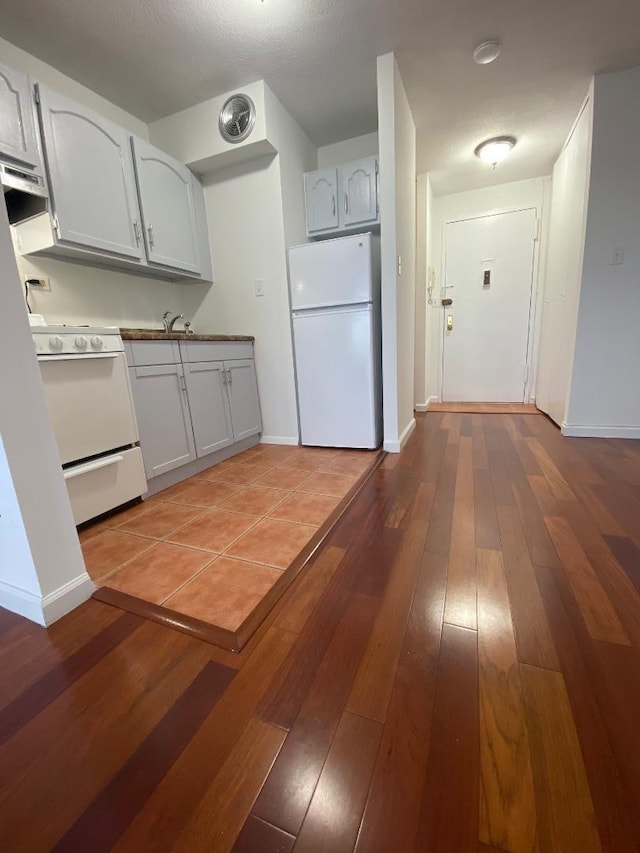 kitchen featuring white appliances, wood-type flooring, visible vents, and baseboards