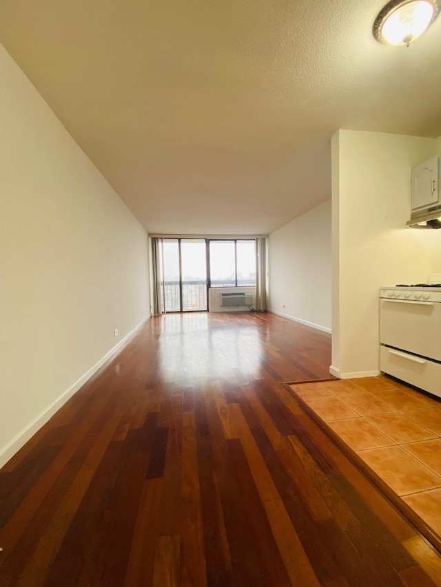 unfurnished living room featuring expansive windows, a textured ceiling, baseboards, and wood finished floors