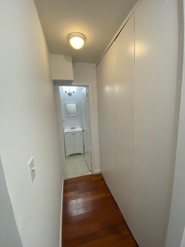 corridor featuring wood-type flooring and a textured ceiling