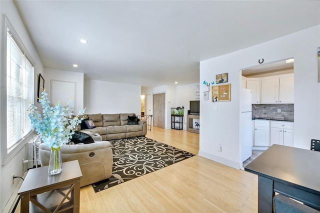 living room featuring baseboards, light wood-type flooring, and recessed lighting