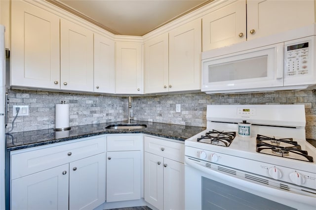 kitchen featuring white appliances, a sink, white cabinetry, decorative backsplash, and dark stone countertops