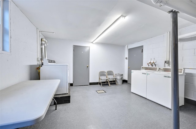 common laundry area with independent washer and dryer and concrete block wall