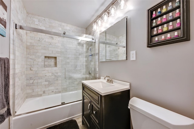 full bath with enclosed tub / shower combo, vanity, and toilet