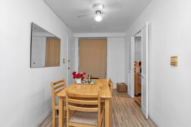 dining space with light wood-style flooring, baseboards, and a ceiling fan