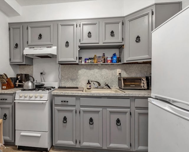 kitchen featuring under cabinet range hood, white appliances, gray cabinetry, and a sink