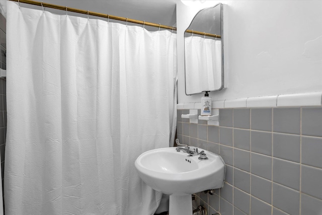 full bathroom with curtained shower, tile walls, and a sink