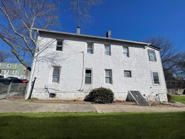 back of property with crawl space, fence, and a chimney