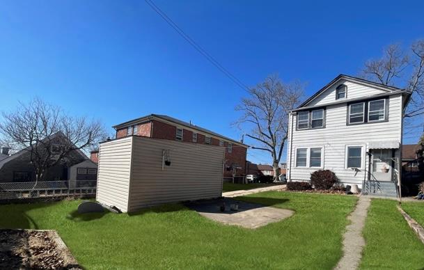 rear view of house featuring a lawn and fence