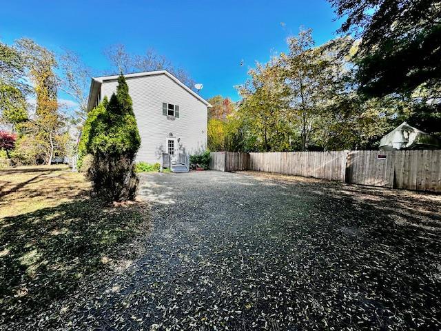 view of property exterior with driveway and fence