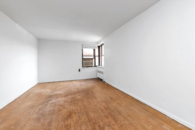 spare room featuring cooling unit, radiator heating unit, baseboards, and wood-type flooring