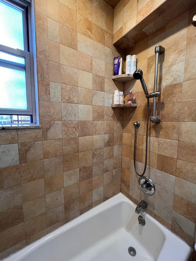 bathroom with washtub / shower combination and a wealth of natural light