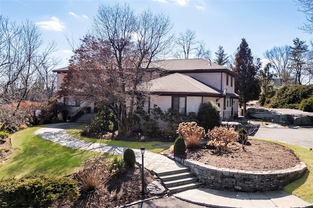 view of property exterior with roof with shingles, a yard, stucco siding, fence, and driveway