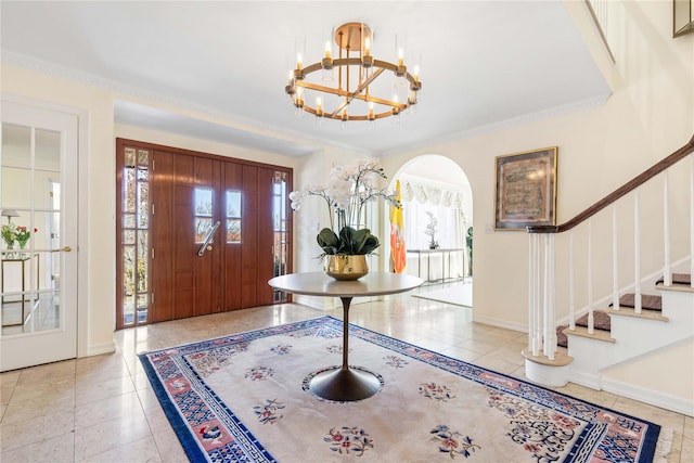 tiled foyer entrance featuring baseboards, arched walkways, stairway, ornamental molding, and an inviting chandelier