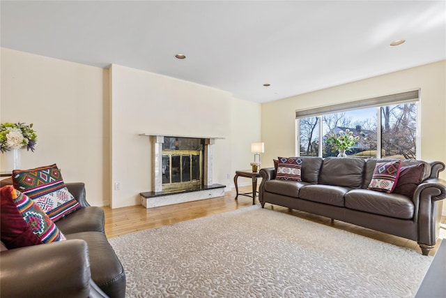 living room featuring recessed lighting, wood finished floors, and a premium fireplace