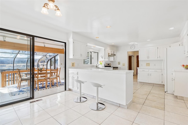 kitchen featuring visible vents, decorative backsplash, a peninsula, light countertops, and light tile patterned flooring