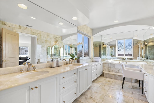 full bath featuring a garden tub, double vanity, a sink, and visible vents