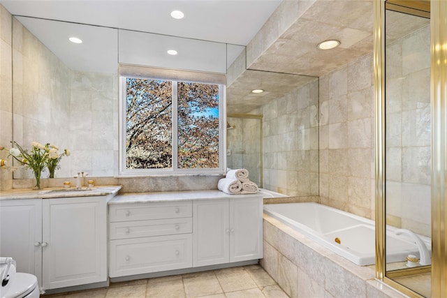 bathroom featuring a relaxing tiled tub, vanity, a shower stall, tile walls, and recessed lighting