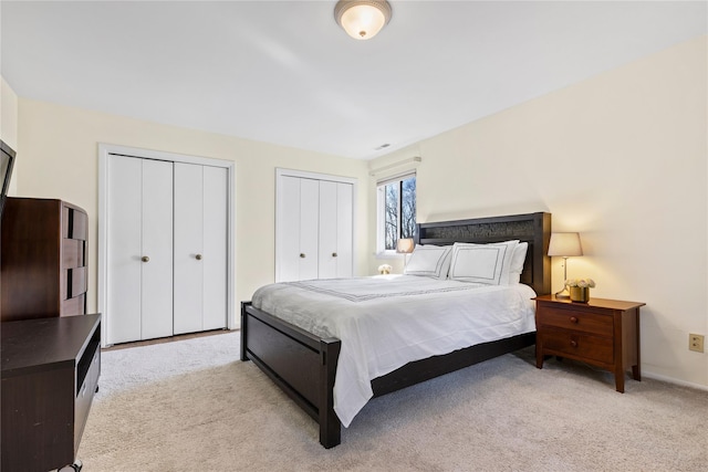 bedroom featuring light carpet and multiple closets