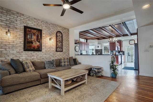 living room featuring beam ceiling, ceiling fan, brick wall, wood finished floors, and baseboards