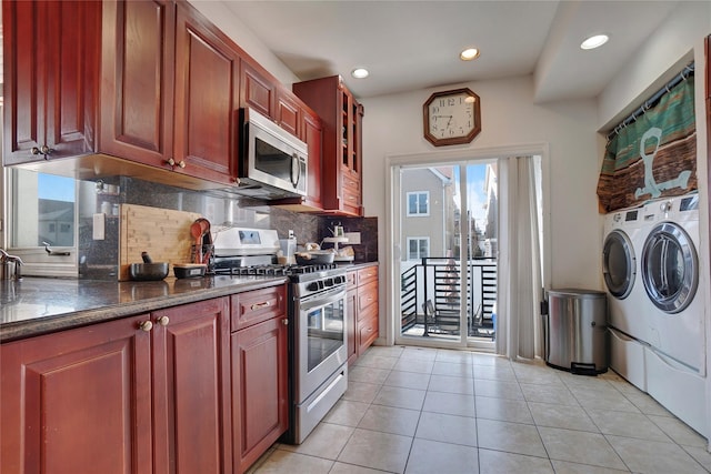 kitchen with reddish brown cabinets, glass insert cabinets, washing machine and clothes dryer, stainless steel appliances, and backsplash