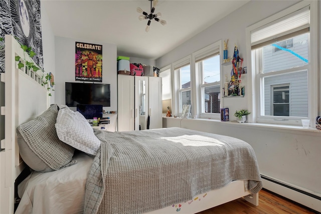 bedroom featuring baseboard heating and wood finished floors