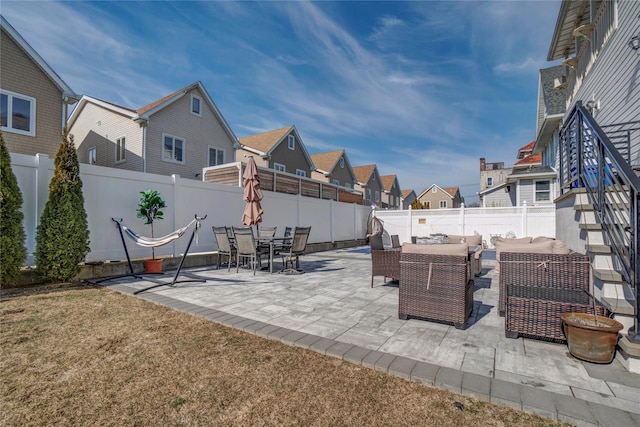 view of patio featuring outdoor dining space, a fenced backyard, and a residential view