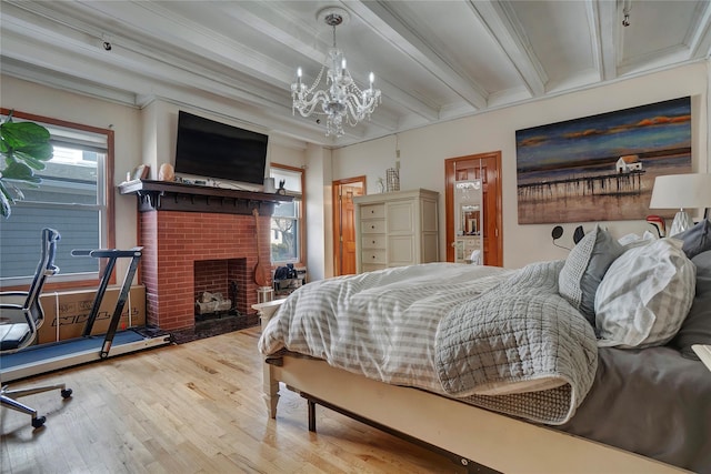 bedroom with beam ceiling, crown molding, an inviting chandelier, a brick fireplace, and wood finished floors