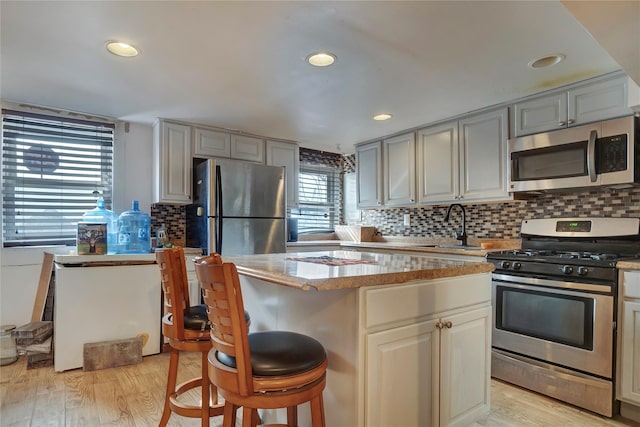 kitchen with stainless steel appliances, a center island, a sink, and light wood-style flooring