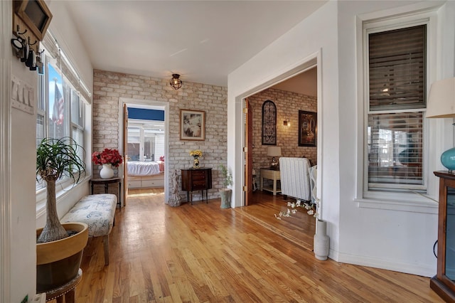 living area with brick wall and light wood-style flooring